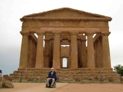 Viaggiatore in carrozzina davanti a un tempio della Valle dei Templi